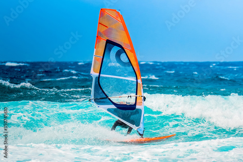 Plakaty Windsurfing  sporty-letnie-windsurfer-na-falach-w-sloneczne-letnie-popoludnie-na-blekitnym-oceanie