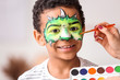 © Pixel-Shot - Woman painting face of African-American boy at home