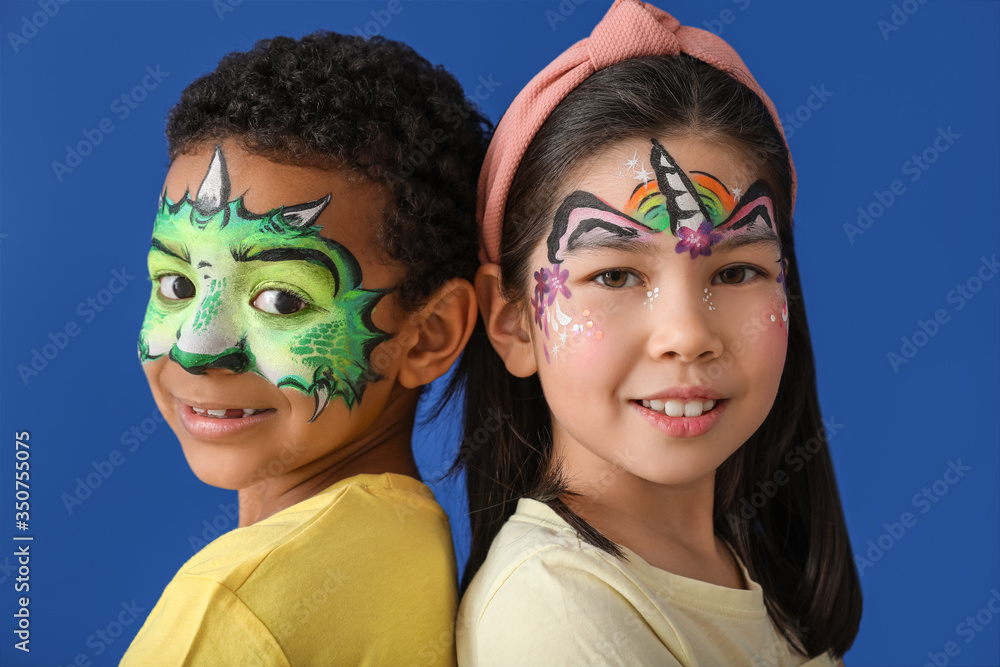 Funny children with face painting on color background