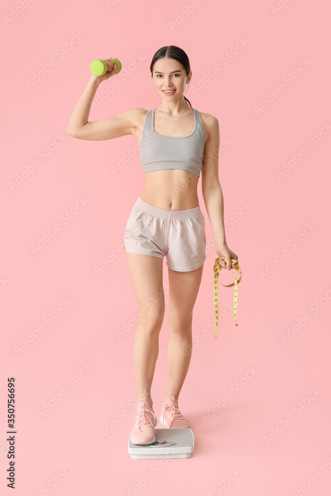 Young woman measuring her weight on color background
