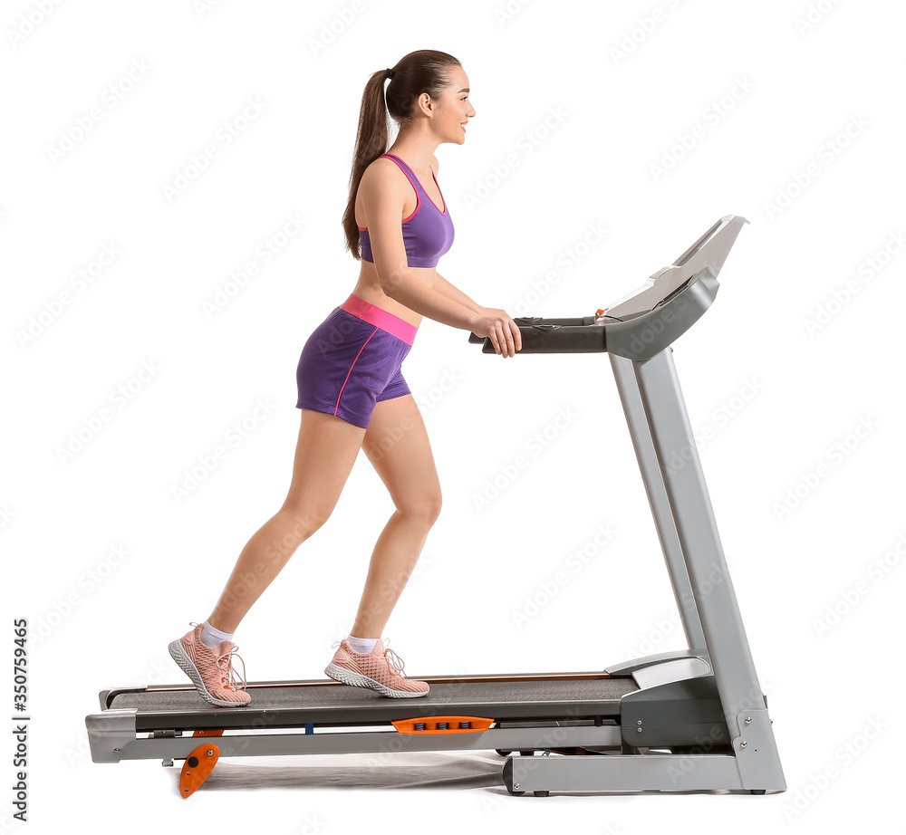 Sporty young woman training on treadmill against white background