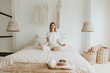 Woman practicing meditation on bed.