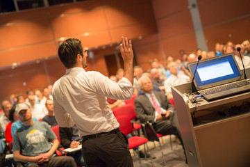 Wall Mural - Speaker at Business Conference with Public Presentations. Audience at the conference hall. Entrepreneurship club. Rear view. Horisontal composition. Background blur.