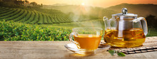 Warm Cup Of Tea With Teapot, Green Tea Leaves On The Wooden Desk At Morning In Plantations With Long Banner Background Empty Space For Text,Organic Product From The Nature For Healthy With Traditional