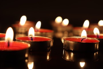 Close-Up Of Candles Burning On Table Against Black Background