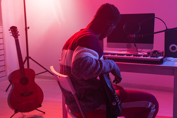 Wall Mural - Create music and a recording studio concept - African american man guitarist recording electric bass guitar track in home studio