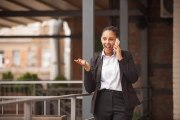 Important call. African-american businesswoman in office attire smiling, looks confident and happy, busy. Finance, business, equality and human rights concept. Beautiful young feme model, successful.