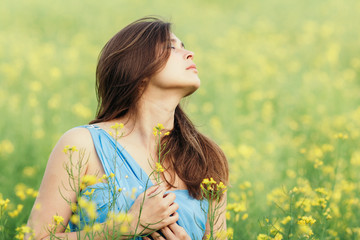 Sticker - beautiful romantic girl on blooming rapeseed field enjoying nature, young elegant woman walks