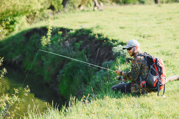 Wall Mural - young fisherman fishes near the river. The concept of outdoor activities and fishing