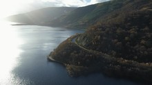 Beautiful Road Bends Around At The Base Of A Mountain. Loch Lomand, Scotland, Sky Reflects Off Of Large Lake