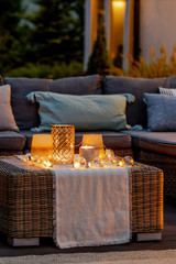 Warm summer night in the garden with trendy furniture, lights, lanterns and candles