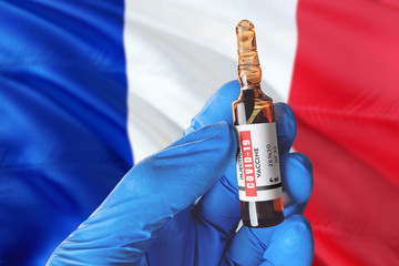 France flag with Coronavirus Covid-19 concept. Doctor with blue protection medical gloves holds a vaccine bottle. coronavirus covid 19 vaccine research.