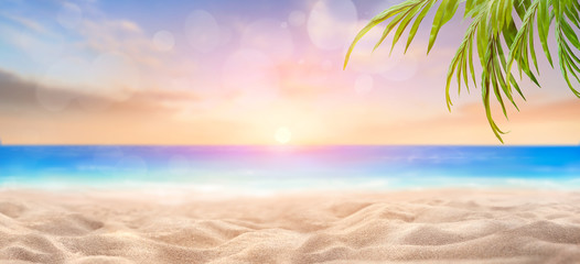 Wall Mural - A summer vacation, holiday background of a tropical beach and blue sea at sunset with the sun on the horizon with bokeh and palm trees.