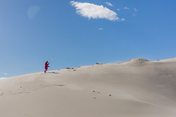 Wall Mural - A teenager is  going up to sandy stack against a clear blue sky. The stack grit,  sandy mound. Concept of difficult way to the destiny.