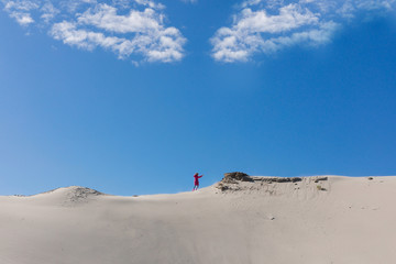 Wall Mural - A teenager is  going up to sandy stack against a clear blue sky. The stack grit,  sandy mound. Concept of difficult way to the destiny.