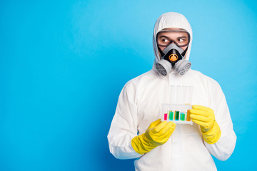 Wall Mural - Portrait of chemist man hold test-tube ncov vaccination look copyspace wear white suit hazmat yellow latex gloves goggles isolated blue color background