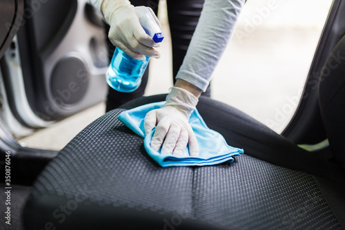Fotomural Woman with protective gloves cleaning car seat with microfiber cloth and spray bottle disinfectant
