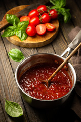 Wall Mural - Classic homemade Italian tomato sauce with basil for pasta and pizza in the pan on wooden background.