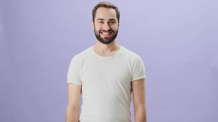 Wall Mural - A cheerful excited man wearing white t-shirt is laughing celebrating success standing isolated over gray background