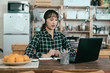 © PR Image Factory - portrait of asian young lady with earphones taking online language course in dining room. Chinese girl sitting straight is repeating new words after teacher. study from home concept