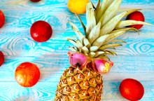 Pineapple In Sunglasses, Red Oranges And Lemons On A Blue Wooden Background. Summer Concept. Fruit, Recreation And Tourism.