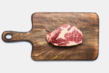 Wall Mural - top view of fresh raw steak on wooden cutting board on white background