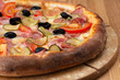 © Mikhail - hearty italian pizza on a wooden board. .pizza with ham, tomatoes, pickles and olives