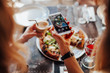 © Julia - Food, eating, technology, culinary and people concept - woman hands with smartphone photographing pizza with girlfriend at restaurant