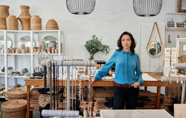 Wall Mural - Young Asian entrepreneur standing by a counter in her store