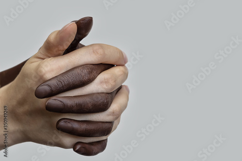 Cuadros en Lienzo Black-and-white human hands in a joint handshake on a gray isolated background, gathered into a fist