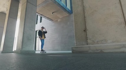 Wall Mural - Young alternative active teenager boy go with skateboard table in urban district with grey walls - concept of youth people z generation on the move