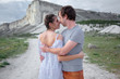 © Вероника Зеленина - Happy couple in relationship walking in the beautiful place. Female dressed white dress and posing against the white mountain cloudy sky. Man hugging his girlfriend
