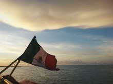 Mexican Flag On Boat Against Cloudy Sky