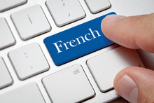 White Computer Keyboard And Blue Button Against French Background.Male Hand Pressing French Written Button On Computer Keyboard.