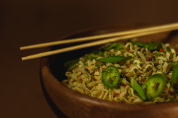 Japanese, Chinese, Asian noodles with hot green pepper on a yellow bed background and a wooden plate