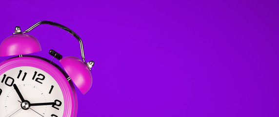 pink alarm clock on purple background