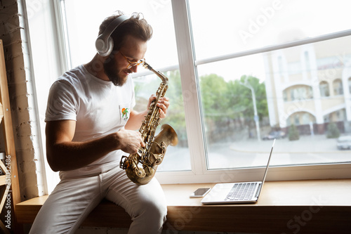 Cuadros en Lienzo Caucasian musician playing saxophone during online concert at home isolated and quarantined