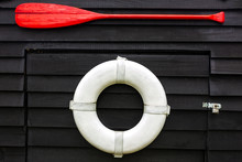 White Lifebuoy And Red Oar On A Black Wall