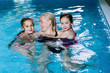 © olenap - Mother with two daughters having fun in indoor swimming-pool. Girl is resting at the water park. Swimming school for small children. Concept friendly family sport summer vacation. Selective focus.