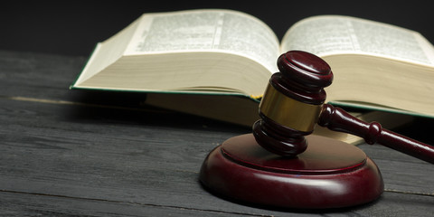 Law concept - Open law book with a wooden judges gavel on table in a courtroom or law enforcement office isolated on white background. Copy space for text