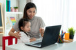 © Prasit Rodphan - Asian kindergarten school girl  with mother video conference e-learning with teacher on laptop in living room at home. Homeschooling and distance learning ,online ,education and internet.
