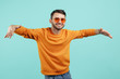 © Screaghin - Handsome bearded young man wearing sunglasses with hands wide open on cyan background.