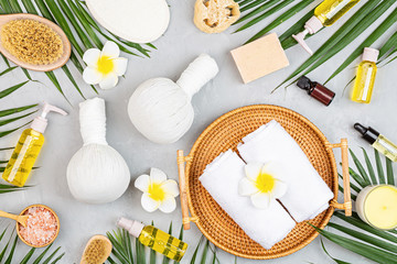 Wall Mural - Spa massage Aromatherapy body care background. Spa herbal balls, cosmetics, towel and tropical leaves on gray concrete table. Top view, flat lay, overhead, copy space. Beauty and health care concept