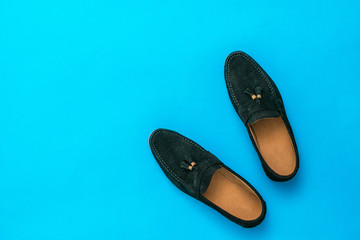 Men's suede loafers on a bright blue background.