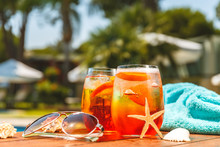 Glasses Of Aperol Spritz Or Negroni Cocktail With Seashells, Towel And Sunglasses At The Summer Patio. Vacation, Summer, Holiday, Luxury Resort Concept. Horizontal Wide Screen Banner Format