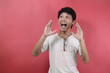 © herukru - Surprised face of happy asian man. Asian men wearing white t shirts isolated on a red background