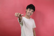 © herukru - Young man looks happy. Asian men wearing white t shirts isolated on a red background