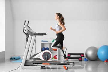 Canvas Print - Sporty young woman training on treadmill in gym