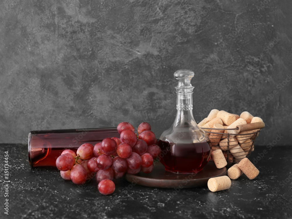 Decanter of wine with corks on dark background