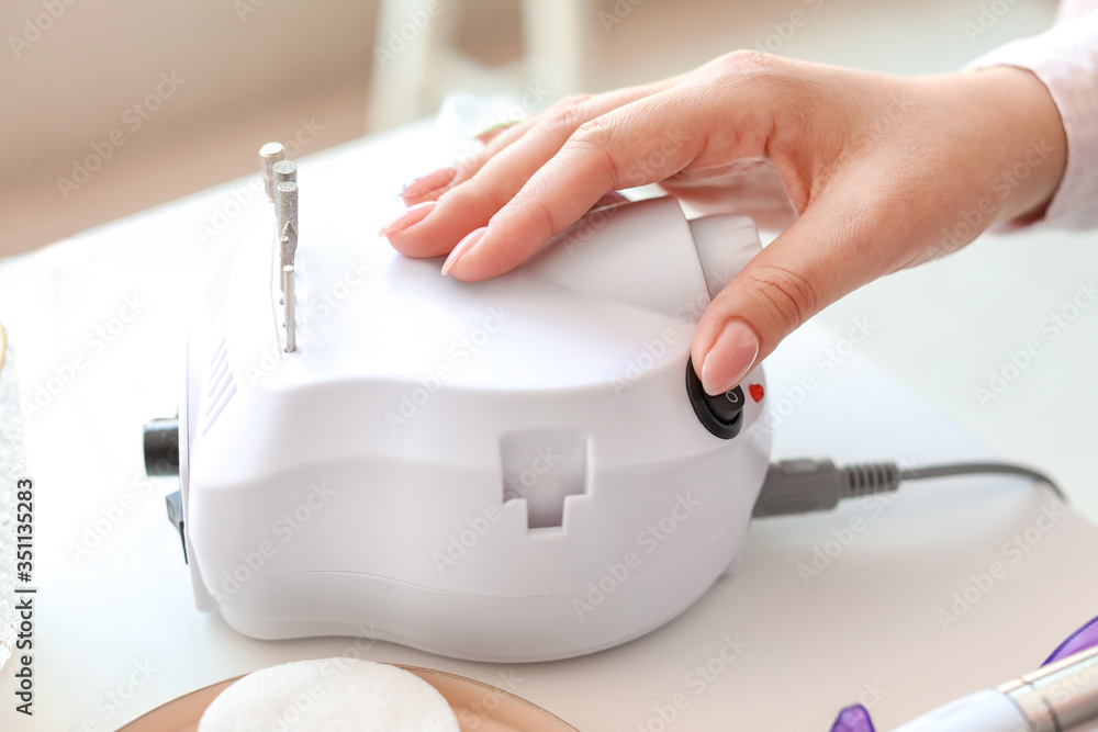 Manicure master working with modern milling cutter in beauty salon, closeup
